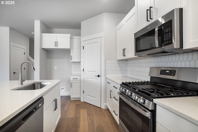 kitchen featuring light countertops, a sink, appliances with stainless steel finishes, and dark wood finished floors