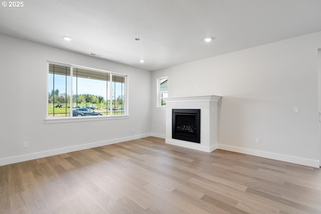 unfurnished living room with a fireplace, recessed lighting, baseboards, and light wood-style flooring
