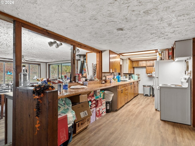 kitchen with washer / dryer, a textured ceiling, and light wood-type flooring