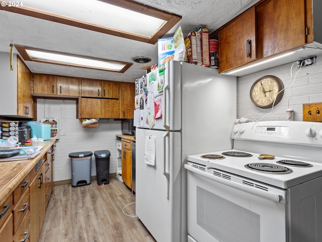 kitchen featuring tasteful backsplash, light wood-type flooring, a textured ceiling, and white appliances