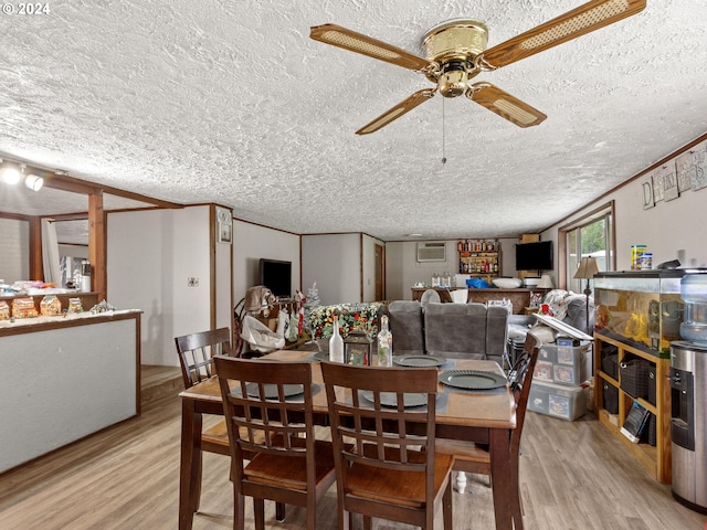 dining space featuring crown molding, ceiling fan, a textured ceiling, and light wood-type flooring