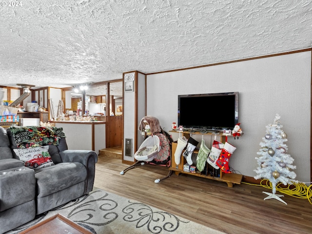 living room with crown molding, wood-type flooring, and a textured ceiling