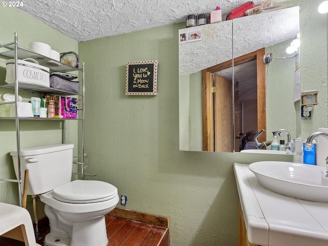 bathroom with vanity, toilet, and a textured ceiling