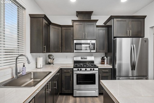 kitchen with dark brown cabinets, dark hardwood / wood-style flooring, stainless steel appliances, and sink