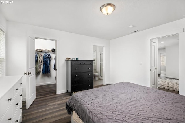 bedroom featuring ensuite bathroom, a spacious closet, a closet, and dark wood-type flooring