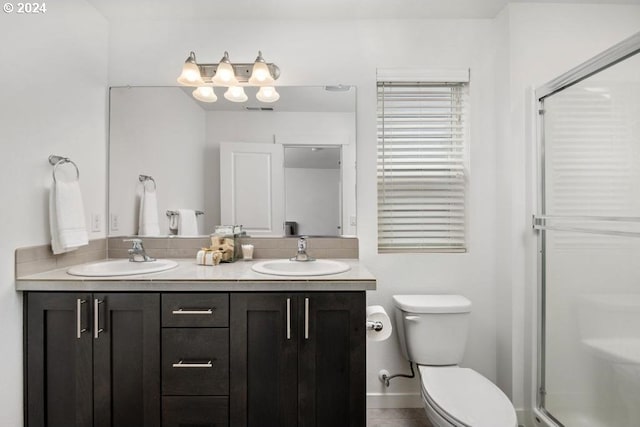 bathroom featuring vanity, toilet, and a shower with door