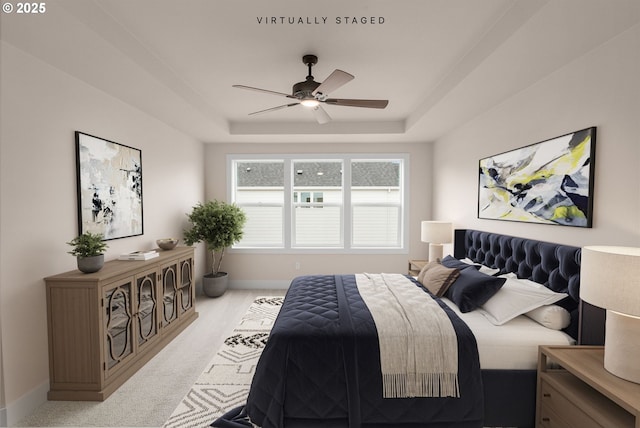 carpeted bedroom with a raised ceiling, ceiling fan, and baseboards