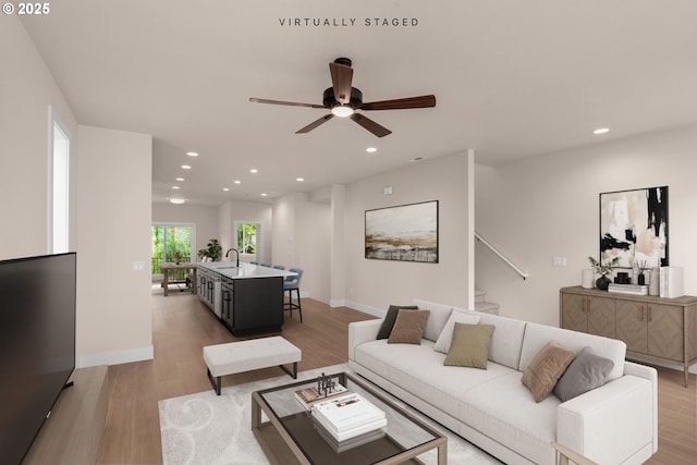 living area featuring ceiling fan, recessed lighting, baseboards, stairway, and light wood finished floors