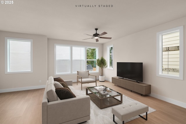 living area with light wood-style flooring, baseboards, and a ceiling fan