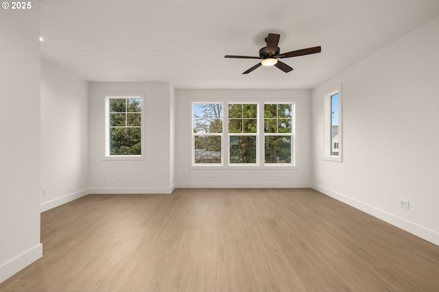 empty room featuring baseboards, ceiling fan, and light wood finished floors