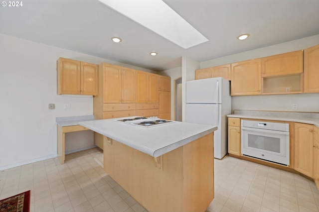 kitchen featuring white appliances, a kitchen breakfast bar, a skylight, light brown cabinetry, and a kitchen island