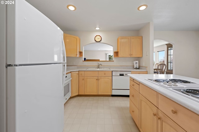 kitchen with light brown cabinets, white appliances, and sink