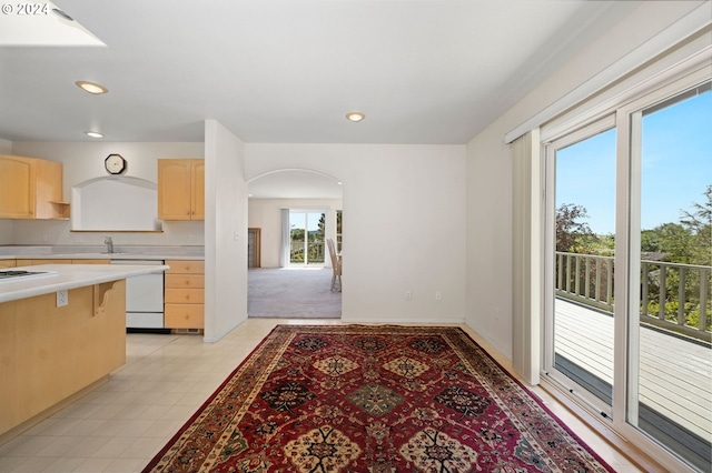 kitchen featuring light brown cabinets, light colored carpet, a healthy amount of sunlight, and white appliances