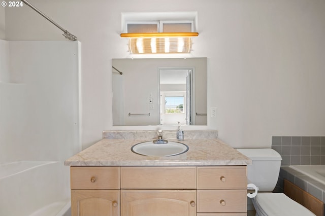 bathroom with vanity, a relaxing tiled tub, and toilet