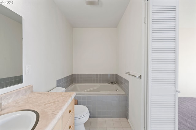 bathroom with tile patterned flooring, vanity, toilet, and tiled bath