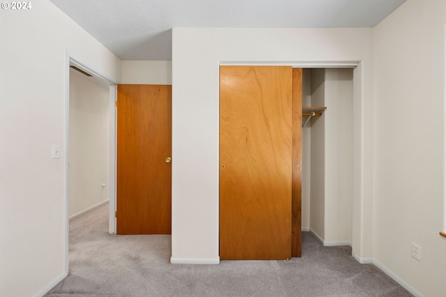 unfurnished bedroom with light carpet and a closet