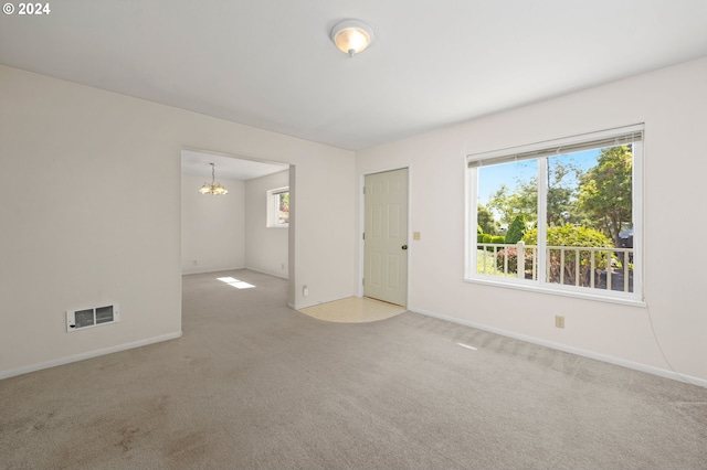 unfurnished room featuring light carpet and a notable chandelier