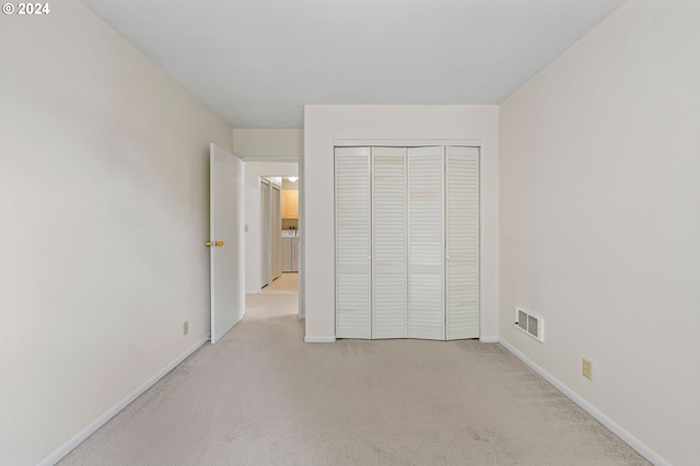 unfurnished bedroom featuring light colored carpet and a closet