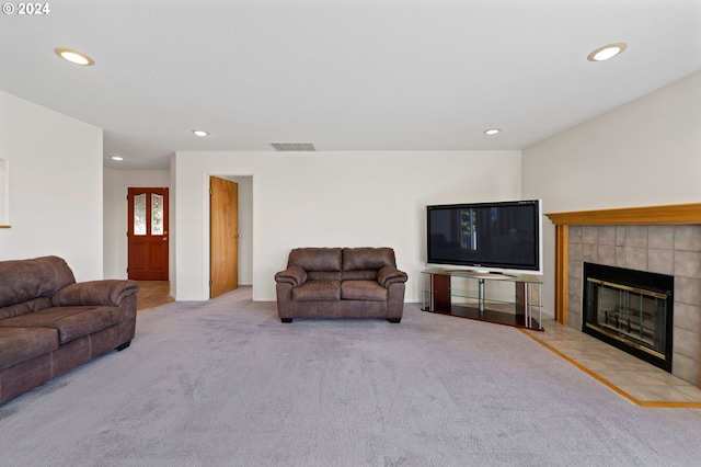 carpeted living room featuring a tiled fireplace