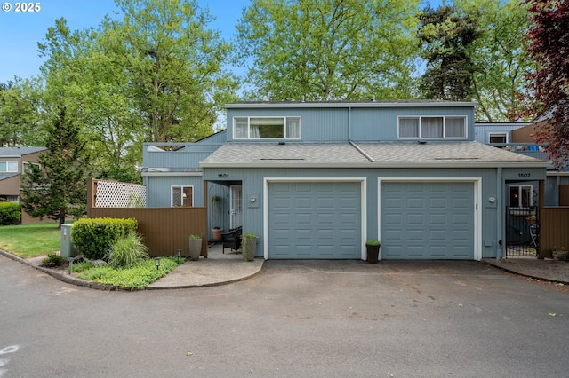 multi unit property with roof with shingles, aphalt driveway, and fence