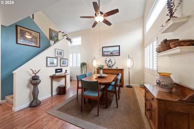 dining space featuring hardwood / wood-style floors, a towering ceiling, ceiling fan, and a healthy amount of sunlight