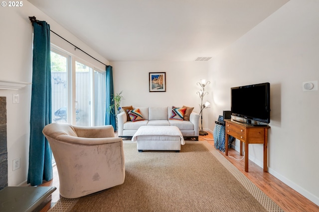 living area featuring visible vents, wood finished floors, baseboards, and a fireplace