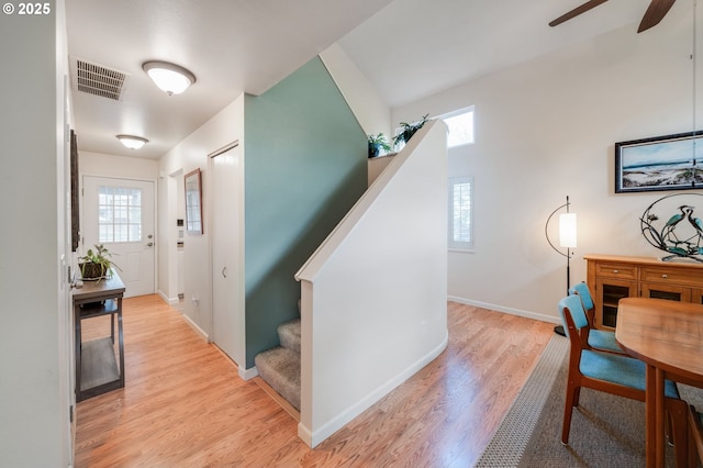 hallway featuring light wood-type flooring, visible vents, baseboards, and stairs