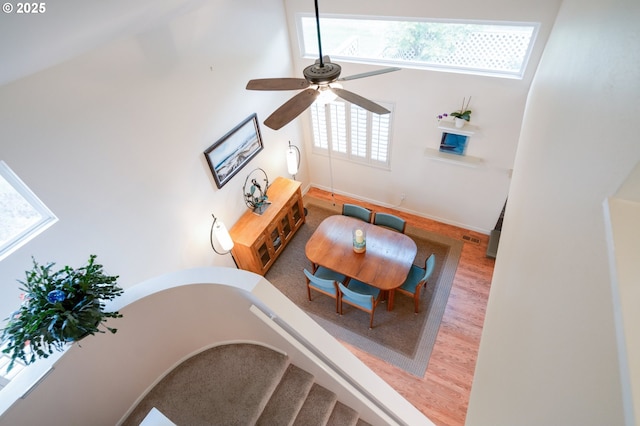living area featuring a ceiling fan, baseboards, a high ceiling, and wood finished floors