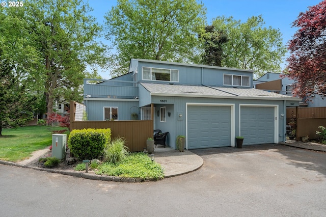 view of front of property with roof with shingles, fence, and aphalt driveway