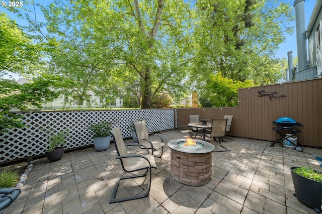 view of patio with an outdoor fire pit and fence