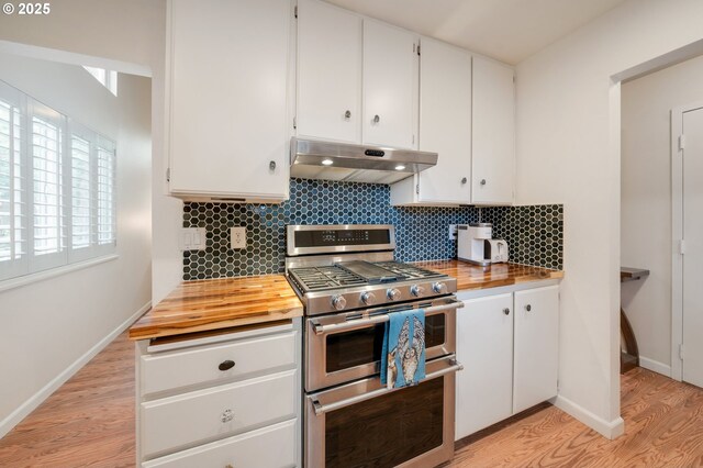 kitchen featuring light wood finished floors, range with two ovens, butcher block countertops, under cabinet range hood, and tasteful backsplash