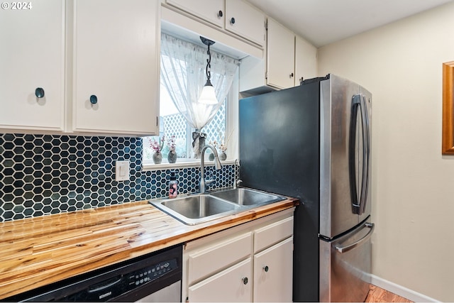 kitchen with sink, hanging light fixtures, tasteful backsplash, white cabinetry, and stainless steel appliances