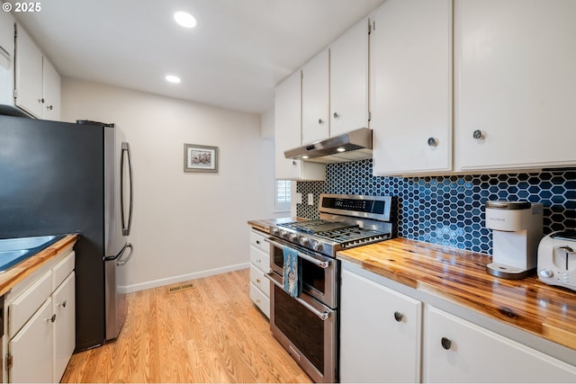 kitchen with wood counters, under cabinet range hood, backsplash, white cabinets, and appliances with stainless steel finishes
