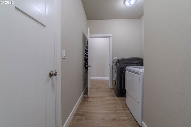 laundry area with washer and dryer and light hardwood / wood-style flooring