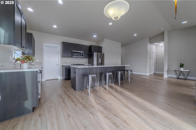 kitchen featuring stainless steel appliances, a breakfast bar area, a center island, and light hardwood / wood-style flooring