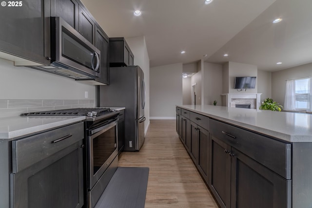 kitchen featuring appliances with stainless steel finishes, light hardwood / wood-style floors, and a center island