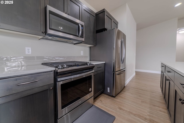 kitchen featuring appliances with stainless steel finishes, light hardwood / wood-style floors, and light stone counters