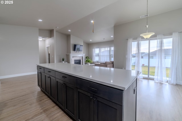 kitchen featuring lofted ceiling, light wood-type flooring, pendant lighting, and a center island