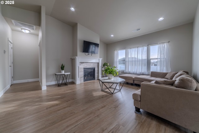 living room featuring lofted ceiling, a fireplace, and hardwood / wood-style flooring