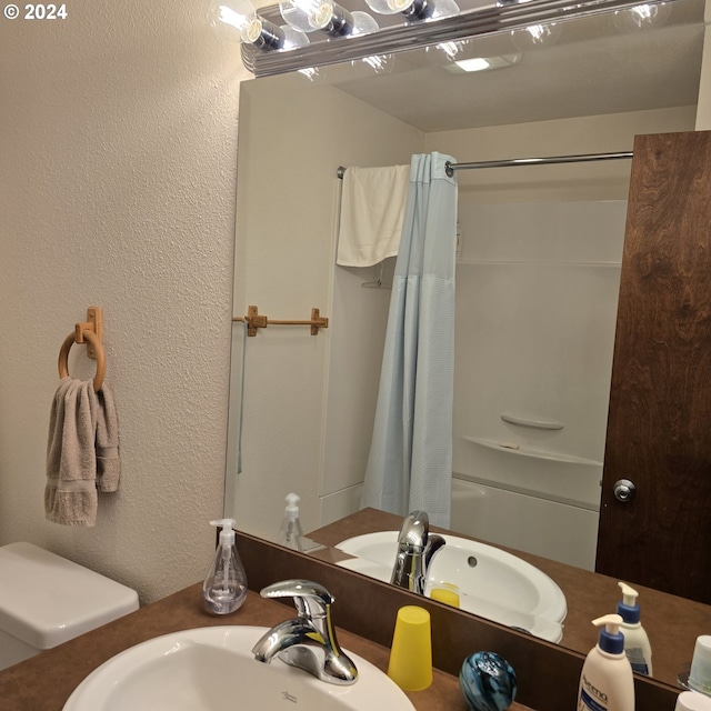 full bathroom featuring sink, shower / bath combo with shower curtain, and toilet