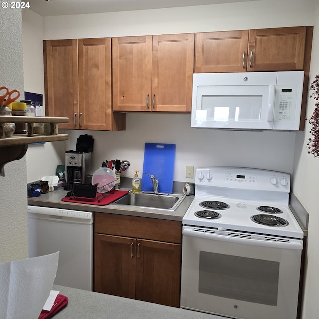 kitchen featuring a sink, light countertops, white appliances, and brown cabinets