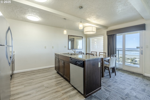 kitchen with dark brown cabinetry, a water view, decorative light fixtures, stainless steel appliances, and light stone countertops