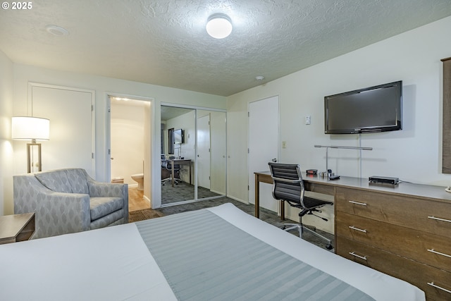 bedroom featuring dark hardwood / wood-style flooring, connected bathroom, and a textured ceiling