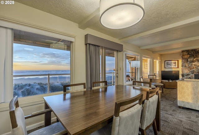 carpeted dining room with beam ceiling and a textured ceiling