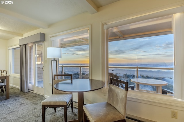 carpeted dining room with beamed ceiling and a water view