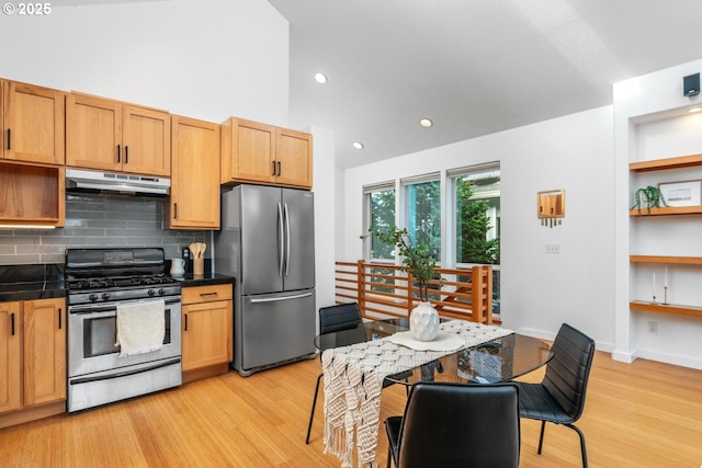 kitchen with a high ceiling, stainless steel appliances, light wood-type flooring, and backsplash