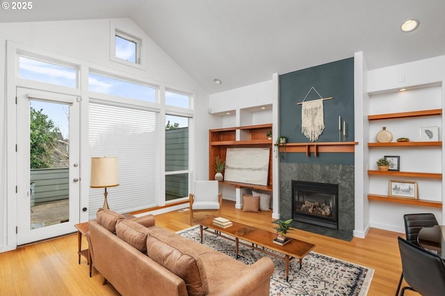 living room featuring a high end fireplace, high vaulted ceiling, built in features, and wood-type flooring