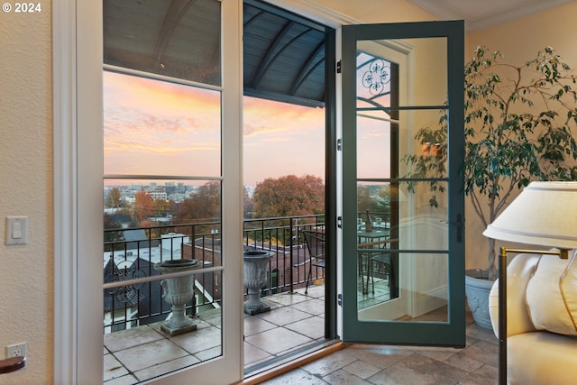 doorway to outside featuring ornamental molding, stone tile flooring, and a textured wall