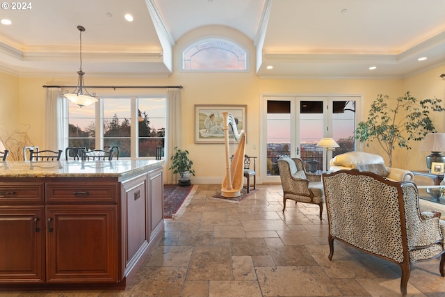 kitchen with stone tile floors, hanging light fixtures, light stone countertops, a tray ceiling, and crown molding