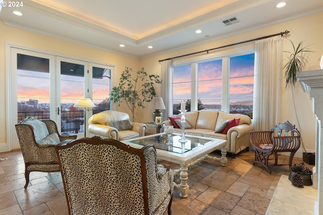 living area with ornamental molding, a tray ceiling, visible vents, and stone tile floors